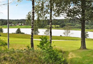 Grüner Landschaftsausblick mit Bäumen und See bei der Hütte '4 Personen Ferienhaus in Frändefors', Schweden.
