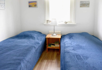 Chambre lumineuse à la maison de vacances à Frändefors, Suède, avec deux lits simples et couvertures bleues.