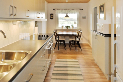 Modern kitchen with dining table and four chairs in a 4 person holiday home in Frändefors, Sweden.