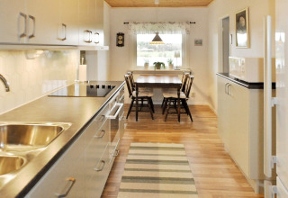 Moderne keuken met eethoek, houten tafel en vier stoelen in een vakantiehuis voor 4 personen in Frändefors, Zweden.
