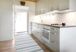 Lichte moderne keuken in een vakantiehuis voor 4 personen in Frändefors, Zweden, met witte kasten en vloer.