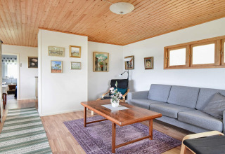 Woonkamer van een vakantiewoning in Frändefors, Zweden, met houten plafond, grijze sofa en muurkunst.