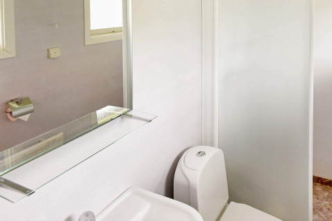 Lichte badkamer in een vakantiehuis in Frändefors, Zweden, met toilet, spiegel en glazen plank.