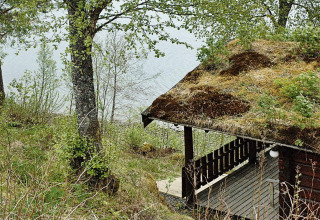 Chalet with a grass-covered roof overlooking a lake and trees, nestled peacefully in rural Sweden.