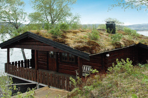 Vakantiechalet met grasdak aan het water in Surna, Zweden, voor vier personen, omgeven door natuur.