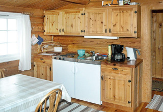 Holzverkleidete Küche im 4-Personen-Ferienhaus in Surna, Schweden, mit Esstisch und Kaffeemaschine.