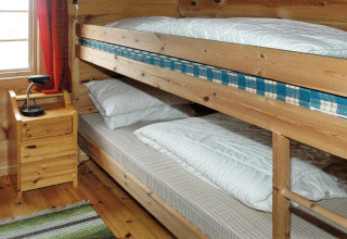 Intérieur de chalet en bois avec lits superposés, table de nuit et lampe dans une maison à Surna, Suède.