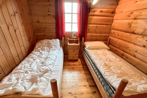 Acogedor dormitorio de madera en el chalet '4 person holiday home in Surna' en Suecia con dos camas individuales.