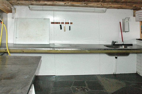 Keukengedeelte in een vakantiehuis in Surna, Zweden, met werkblad, gootsteen, messen en snijplank.