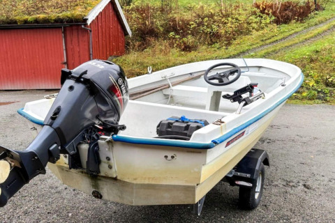 Small motorboat with outboard engine parked by a red cabin, pictured at '4 person holiday home in Surna'.