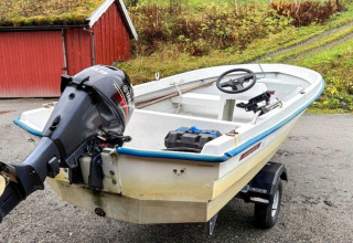Kleine motorboot voor een rood huisje, gefotografeerd aan chalet '4 person holiday home in Surna' in Zweden.