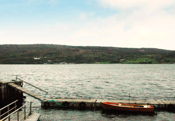 Vue sur un lac avec une petite barque près du ponton au chalet pour 4 personnes à Surna, Suède.