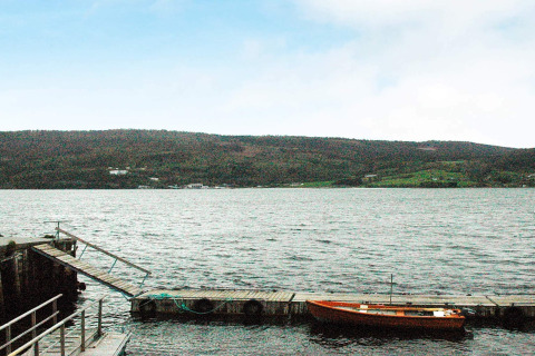 Vue sur un lac avec une petite barque près du ponton au chalet pour 4 personnes à Surna, Suède.