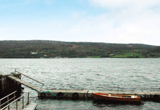 Vista su un lago con una piccola barca al molo presso la casa vacanze per 4 persone a Surna, Svezia.