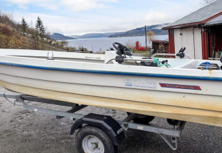 Small motorboat on trailer beside a holiday home, lake and mountains, 4 person house in Surna, Sweden.