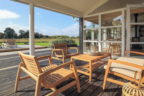 Terrazza soleggiata con mobili in legno presso casa vacanze a Øster Assels, Danimarca.