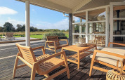 Sonnige Terrasse mit Holzmöbeln am Ferienhaus in Øster Assels, Dänemark, Blick ins Grüne.