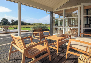 Terrazza soleggiata con mobili in legno presso casa vacanze a Øster Assels, Danimarca.