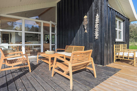 Udendørs terrasse ved 6-personers feriehus i Øster Assels, Danmark, med moderne havemøbler i træ.