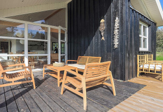 Terrasse eines 6-Personen-Ferienhauses in Øster Assels, Dänemark, mit Holzstühlen und moderner Deko.