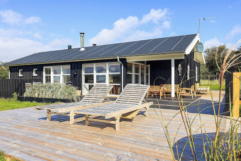 Buitenaanzicht van 6-persoons vakantiewoning in Øster Assels, Denemarken, met houten terras en ligstoelen.