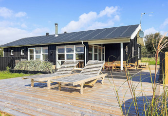 Vista esterna della casa vacanze per 6 persone a Øster Assels, Danimarca, con terrazza in legno e sdraio.
