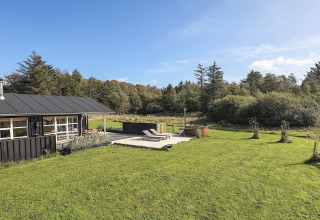 Buitenaanzicht van een vakantiehuis met terras, ligstoelen en hottub in Øster Assels, Denemarken.