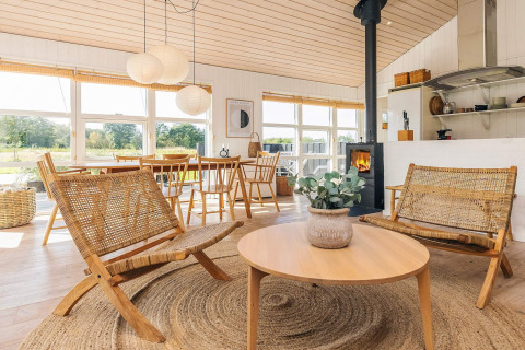Gezellige, lichte woonkamer in vakantiewoning in Øster Assels, Denemarken, met houten meubels en grote ramen.