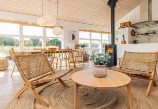 Salón luminoso y acogedor en casa de vacaciones en Øster Assels, Dinamarca, con muebles de madera y ventanales.