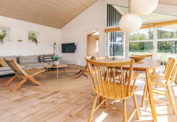 Soggiorno luminoso e moderno nella casa vacanze di Øster Assels, Danimarca, con mobili in legno e finestre.