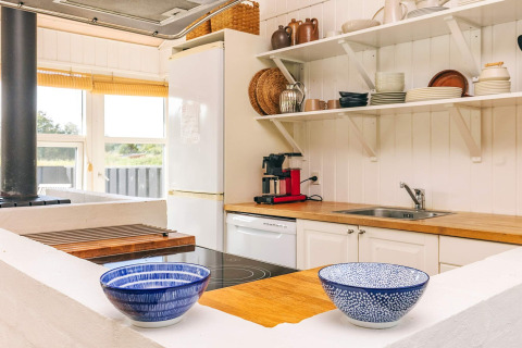 Lyst køkken i et feriehus i Øster Assels, Danmark, med åbne hylder og træbordplade.