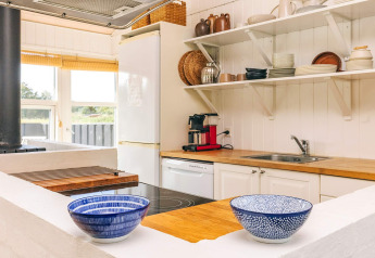 Helles Ferienhaus-Küche in Øster Assels, Dänemark, mit Holzarbeitsplatte und offenen Regalen.