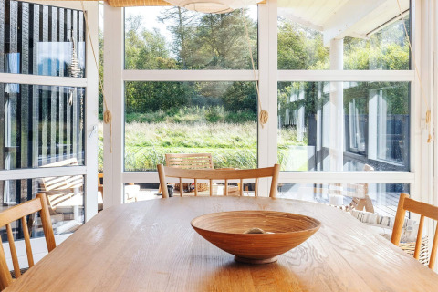 Zona pranzo luminosa nella casa vacanze per 6 persone a Øster Assels, Danimarca, con grandi finestre e legno.