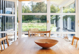 Zona pranzo luminosa nella casa vacanze per 6 persone a Øster Assels, Danimarca, con grandi finestre e legno.