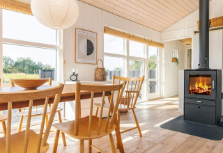 Lichte vakantiewoning in Øster Assels, Denemarken met eetruimte, houtkachel en grote ramen naar buiten.