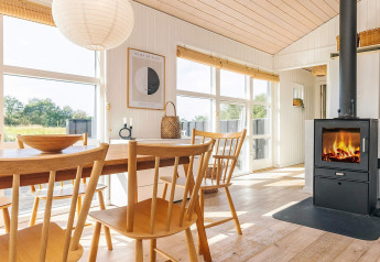 Lichte vakantiewoning in Øster Assels, Denemarken met eetruimte, houtkachel en grote ramen naar buiten.