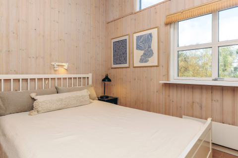 Slaapkamer in een vakantiewoning in Øster Assels, Denemarken, met houten muren en een ruim venster.