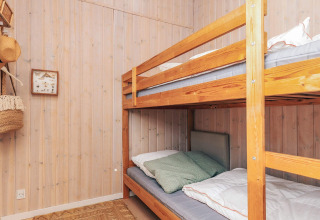Zimmer mit Etagenbett und Holzverkleidung in einem Ferienhaus für 6 Personen in Øster Assels, Dänemark.