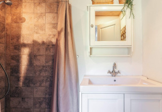 Bagno moderno con lavandino, armadietto con specchio, doccia e piastrelle marroni in una casa vacanza a Øster Assels, Danimarca.