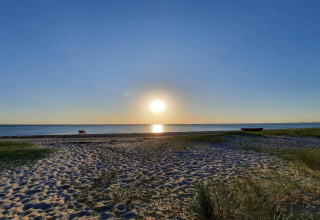 Solnedgang på stranden ved '6 personers feriehus i Store Fuglede', Danmark, med båd og roligt hav.