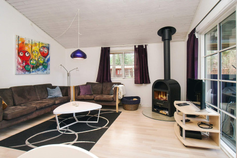 Woonkamer in chalet in Store Fuglede, Denemarken met haard, moderne banken, kunst en grote ramen.