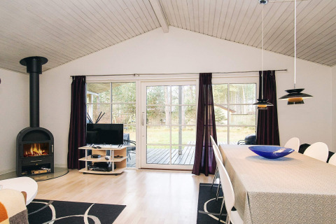 Lichte woonkamer in een vakantiehuis in Store Fuglede, Denemarken, met open haard en eethoek aan tuin.