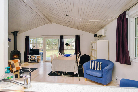 Stue i chalet '6 personers feriehus i Store Fuglede' i Danmark med spisebord, pejs og udsigt til have.
