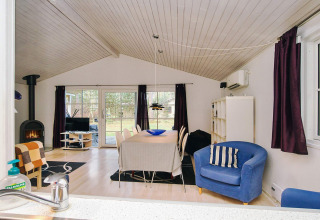 Stue i chalet '6 personers feriehus i Store Fuglede' i Danmark med spisebord, pejs og udsigt til have.