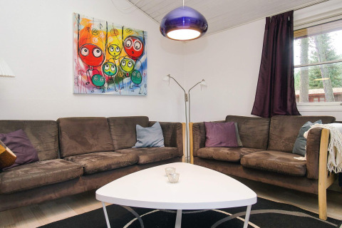 Woonkamer met bruine zetels, kleurrijk schilderij en moderne lamp in chalet in Store Fuglede.