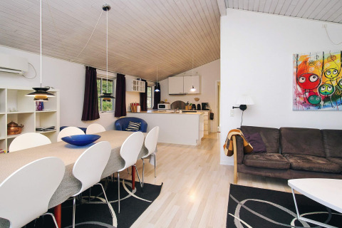 Woon- en eetkamer in een vakantiehuis in Store Fuglede, Denemarken, met moderne meubels en kleurrijke kunst aan de muur.