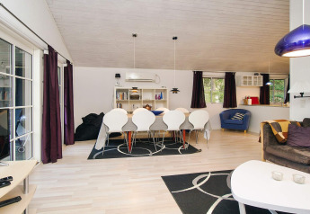Moderne stue og spisestue i et feriehus i Store Fuglede, Danmark, med lyst træinteriør og elegant indretning.