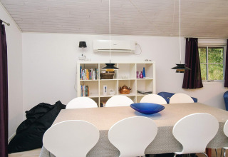 Eetkamer van vakantiehuis in Store Fuglede, Denemarken, met witte stoelen, eettafel en open boekenkast.