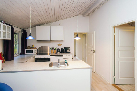 Cocina moderna en una casa de vacaciones en Store Fuglede, Dinamarca, con armarios blancos y luces azules.