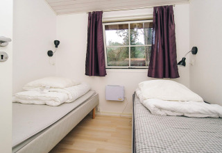 Dormitorio con dos camas individuales, cortinas moradas y ventana en casa de vacaciones para 6 personas en Store Fuglede, Dinamarca.